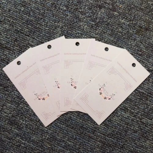 A photo showcasing a custom clothing hang tag. The hang tag features the brand name, logo, and other customized information.