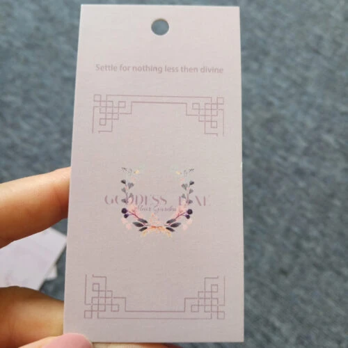 A photo showcasing a custom clothing hang tag. The hang tag features the brand name, logo, and other customized information.