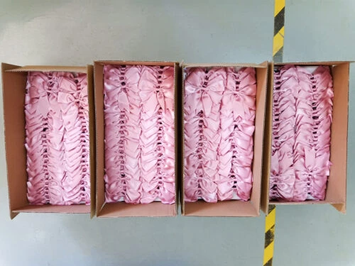 This image displays neatly arranged bows placed inside small cardboard boxes to ensure they remain unfolded or wrinkled during transportation. This meticulous packaging ensures the integrity and aesthetics of the products.