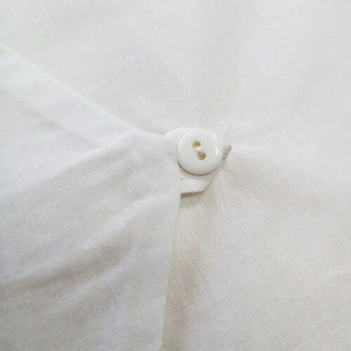 صورة مقربة للزر الموجود على غطاء حقيبة تخزين مصنوعة من القطن على شكل مظروف.