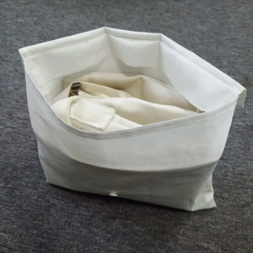 حقيبة تخزين على شكل مظروف من القطن مع محتويات، واقفة بشكل مستقيم.