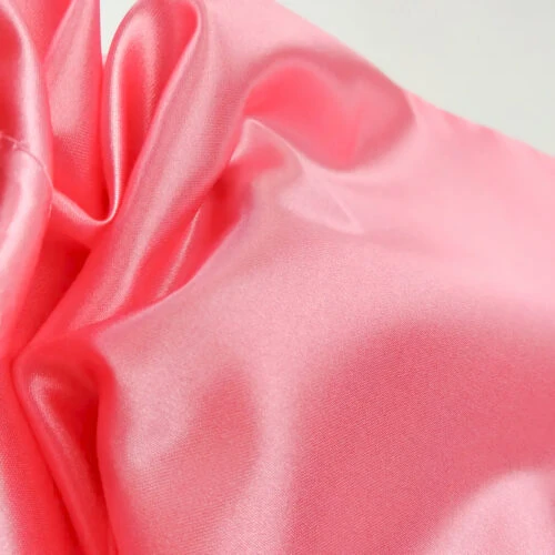 صورة مقربة لنسيج حقيبة ساتان وردية اللون مطبوع عليها اسم العلامة التجارية للعميل والبريد الإلكتروني وحساب إنستغرام وفيسبوك. الحقيبة مزينة بصورة ظلية لامرأة ذات شعر جميل.