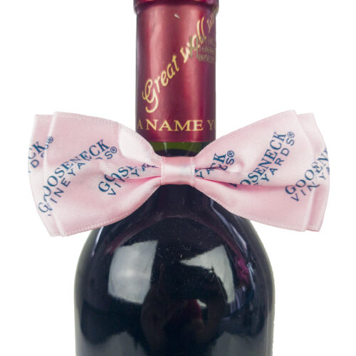 Pink bow tie with blue logo, displayed on the neck of a wine bottle