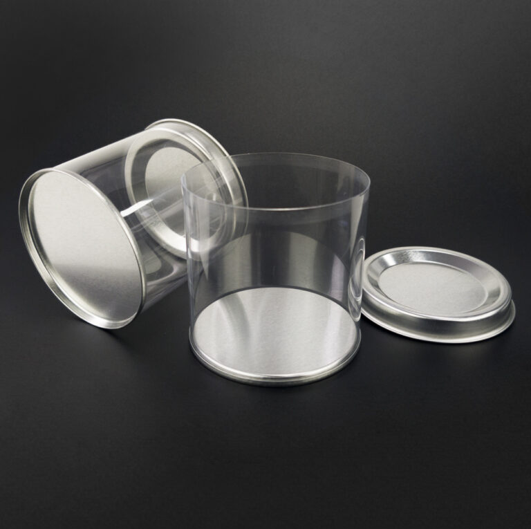 Tube en plastique avec couvercle en étain debout et tube en plastique avec couvercle en étain couché horizontalement, avec le couvercle du tube vertical ouvert et placé de côté.