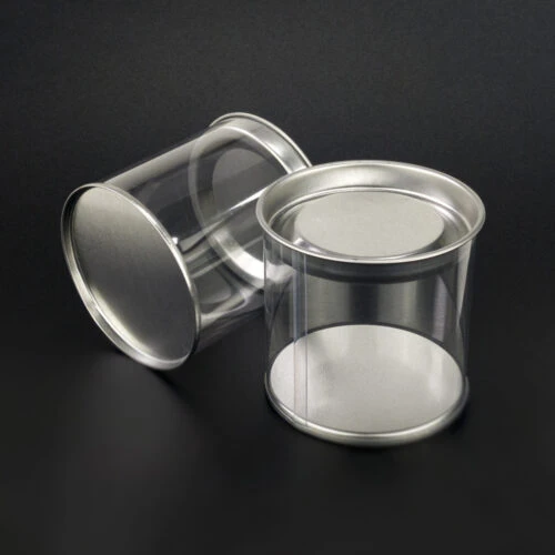 Plastic tube with tin lid standing upright and plastic tube with tin lid lying horizontally.