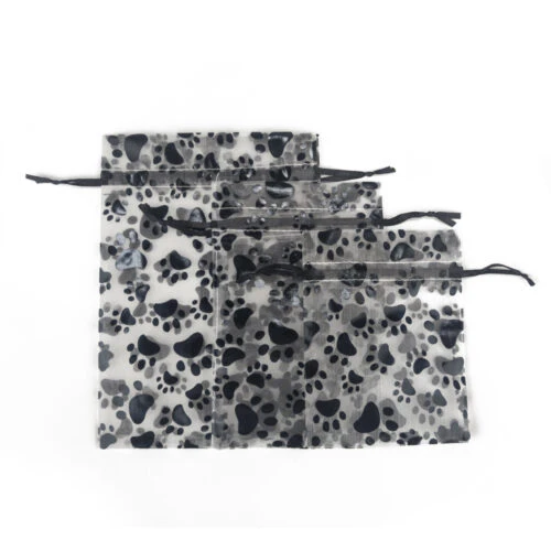 犬の足跡オーガンザ巾着バッグ - 3 つの異なるサイズの犬の足跡オーガンザ巾着バッグを平らな場所に並べました。