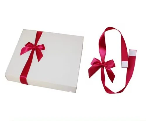 Individuell gestaltete Schleifen aus Klebebändern sind elegant an eine Geschenkschachtel gebunden, eine andere wird mit selbstklebender Rückseite präsentiert und zeigt so die einfache Anwendung für Dekorationszwecke.