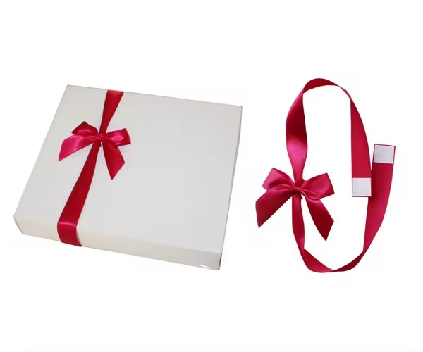 أقواس من شريط لاصق مخصص يتم ربطها بشكل أنيق على صندوق هدايا وأخرى معروضة بظهرها اللاصق، مما يوضح سهولة الاستخدام لأغراض الديكور.