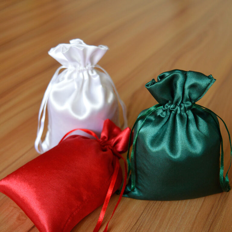 Trois sacs en soie personnalisés aux couleurs blanc, rouge et vert, parfaits pour ranger des bijoux ou des cadeaux de mariage.