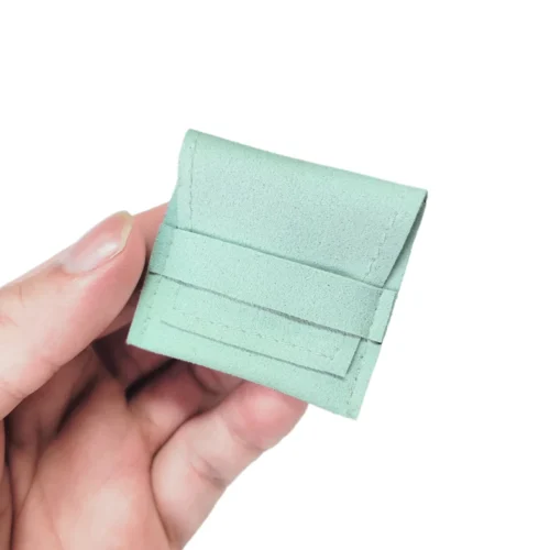 Customizable Microfiber Suede Ring Pouch held between fingers, showcasing its compact size and smooth texture.