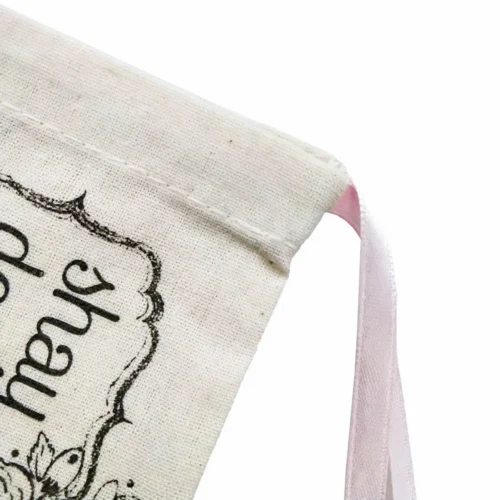 プリントデザインとピンクの引き紐が部分的に見える、天然素材で作られたカスタマイズ可能な引き紐ポーチ。