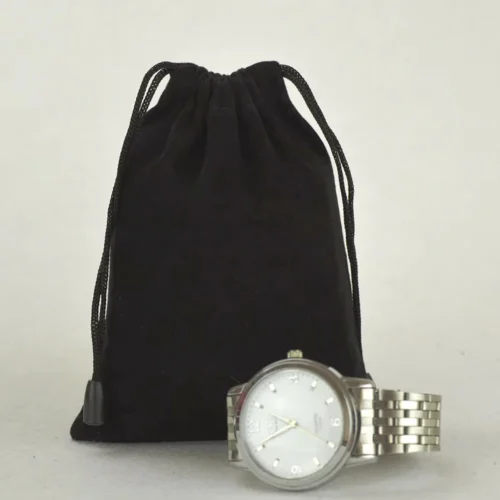 Custom black velvet drawstring bag next to a silver watch, showcasing its elegant design.