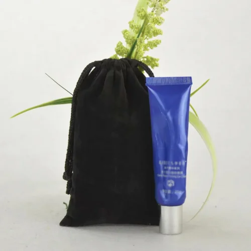 Custom black velvet drawstring bag next to a blue tube, showcasing the bag's elegant design.