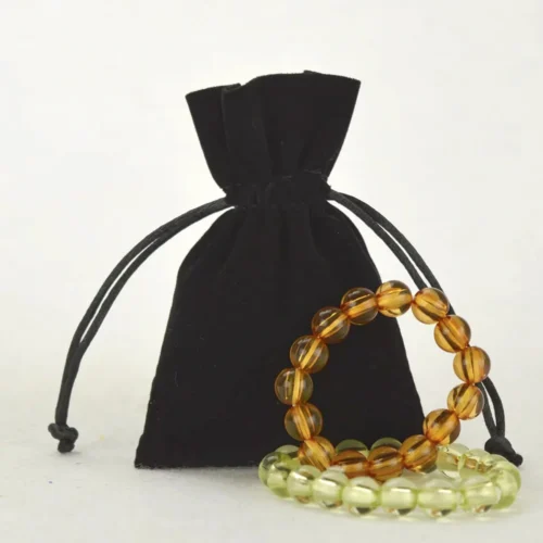 Custom black velvet drawstring bag with decorative bracelets, showcasing the bag's design and texture.