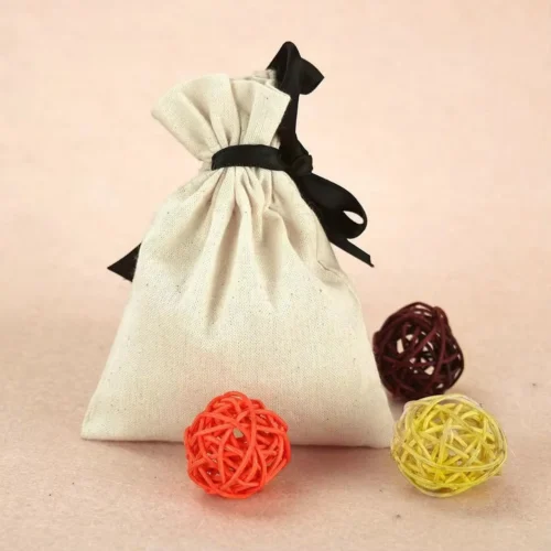 حقيبة مخصصة برباط مصنوعة من قماش طبيعي، تتميز بشريط أسود اللون محاط بكرات ملونة مزخرفة.