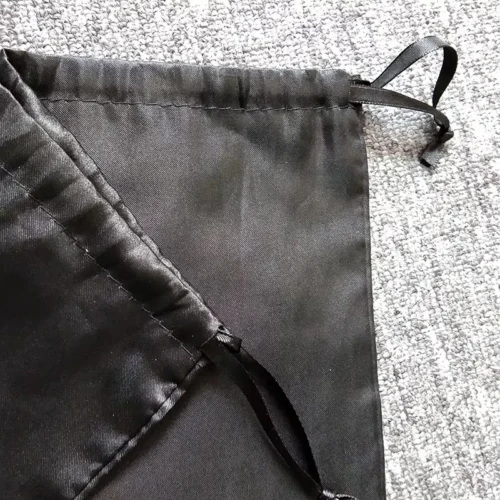 Gros plan d'un sac de maillot de bain personnalisé imperméable à cordon de serrage en satin noir, mettant en valeur la fermeture à cordon.