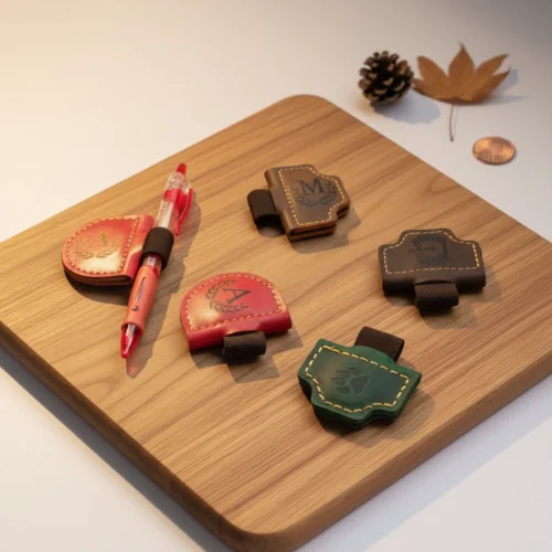 Collection d'échantillons de marque-pages magnétiques en cuir présentés sur une planche en bois avec un stylo et des accessoires de saison.