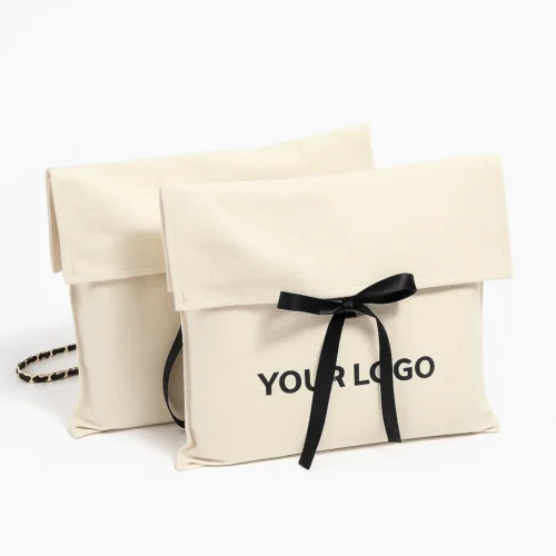 Front-view sample of cream custom fold over pouches with black ribbon ties on a white background.