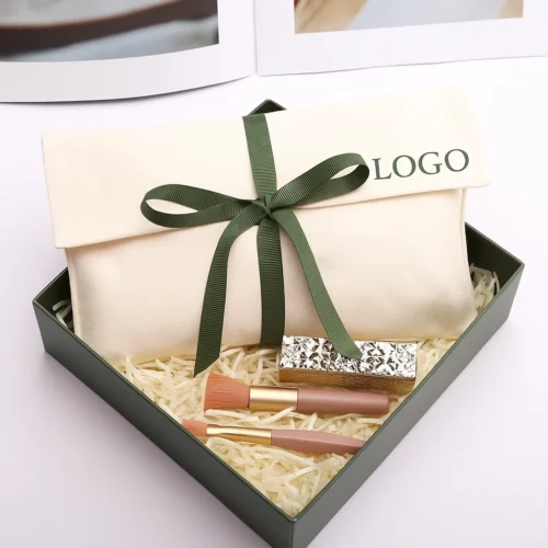 Example of a custom fold over pouch in cream cotton with a green ribbon, shown as a gift-box presentation.