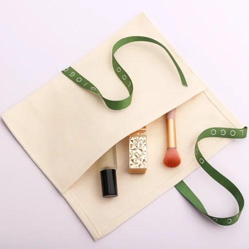 Example of a custom fold over pouch in cream cotton fabric with ribbon tie, shown open with cosmetics inside.