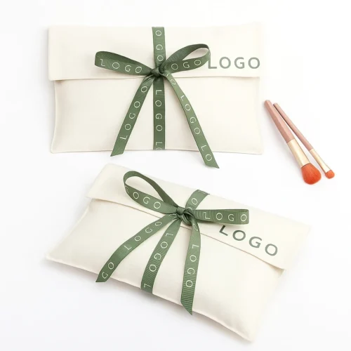 Example of a custom fold over pouch in cream fabric with green ribbon, shown as a gift-styled flat-lay.