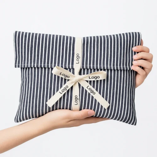 Striped fabric custom fold over pouch held in hands, shown as a sample for patterned options and ribbon customization.