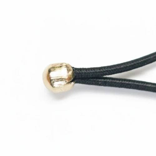 Close-up of a Menu Cord with Metal Ball showing the reinforced connection between the black elastic rope and the gold metal bead fastener.