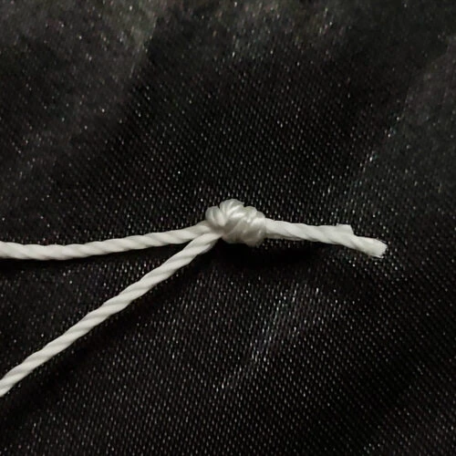 Detail view of the knot on a Pre-Tied Tufting Loop, the 3-strand high-tensile nylon tied and heat-set to keep the loop secure for deep-button upholstery.