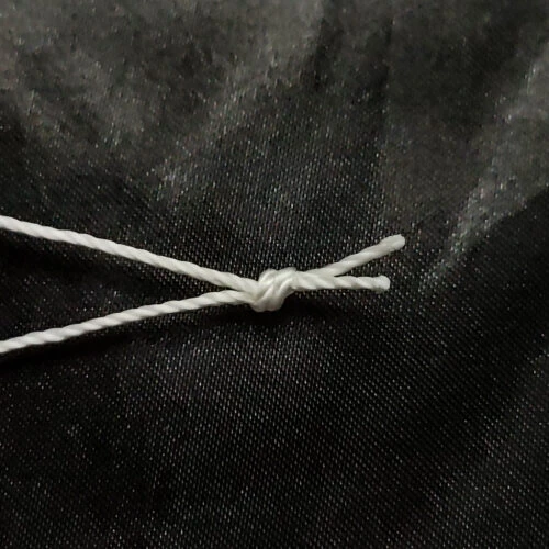 Close-up of the end knot on a Pre-Tied Tufting Loop, showing the 3-strand nylon cord tied firm so it will not slip during upholstery button setting.