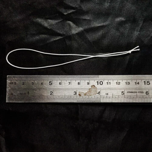 Pre-Tied Tufting Loops in white 3-strand high-tensile nylon, a single knotted loop laid beside a ruler to show overall loop size for deep-button sofa upholstery.